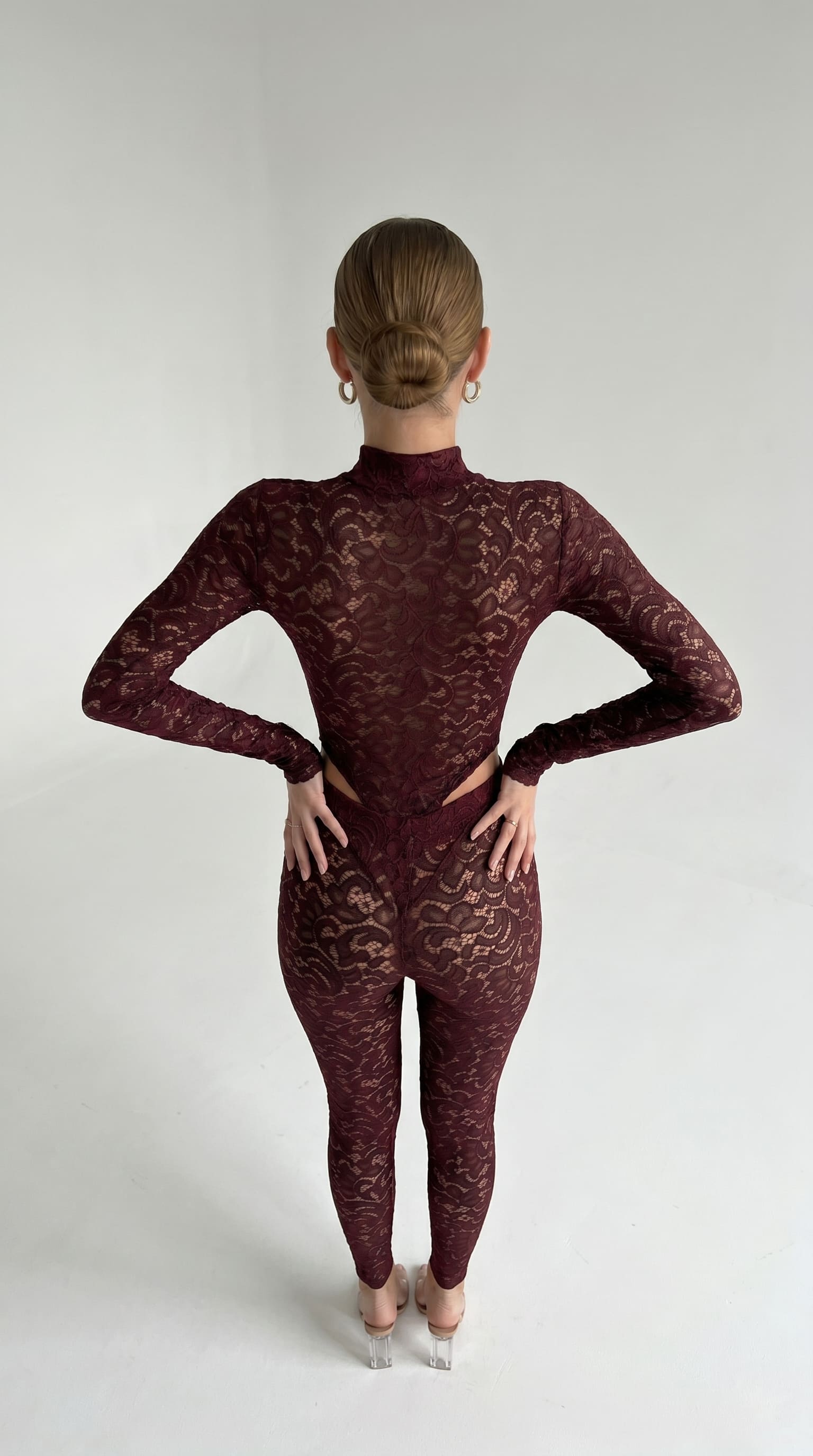 Back view of a burgundy lace catsuit, highlighting the open, cutout back design.