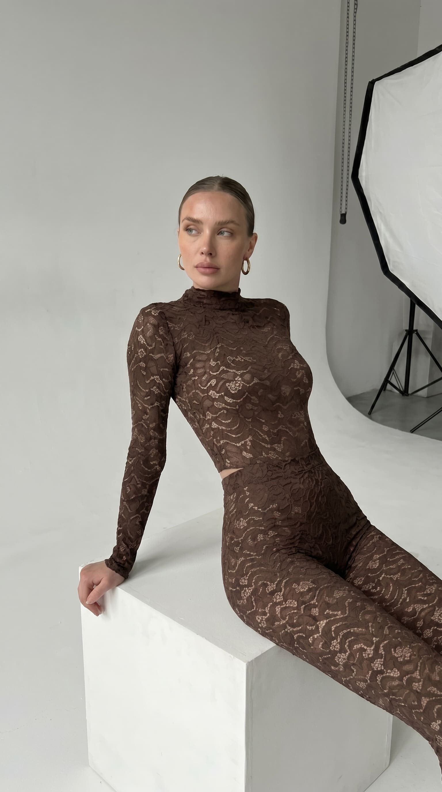 Cinematic back view of the brown Iness de Nuit lace suit featuring custom architectural tailoring.