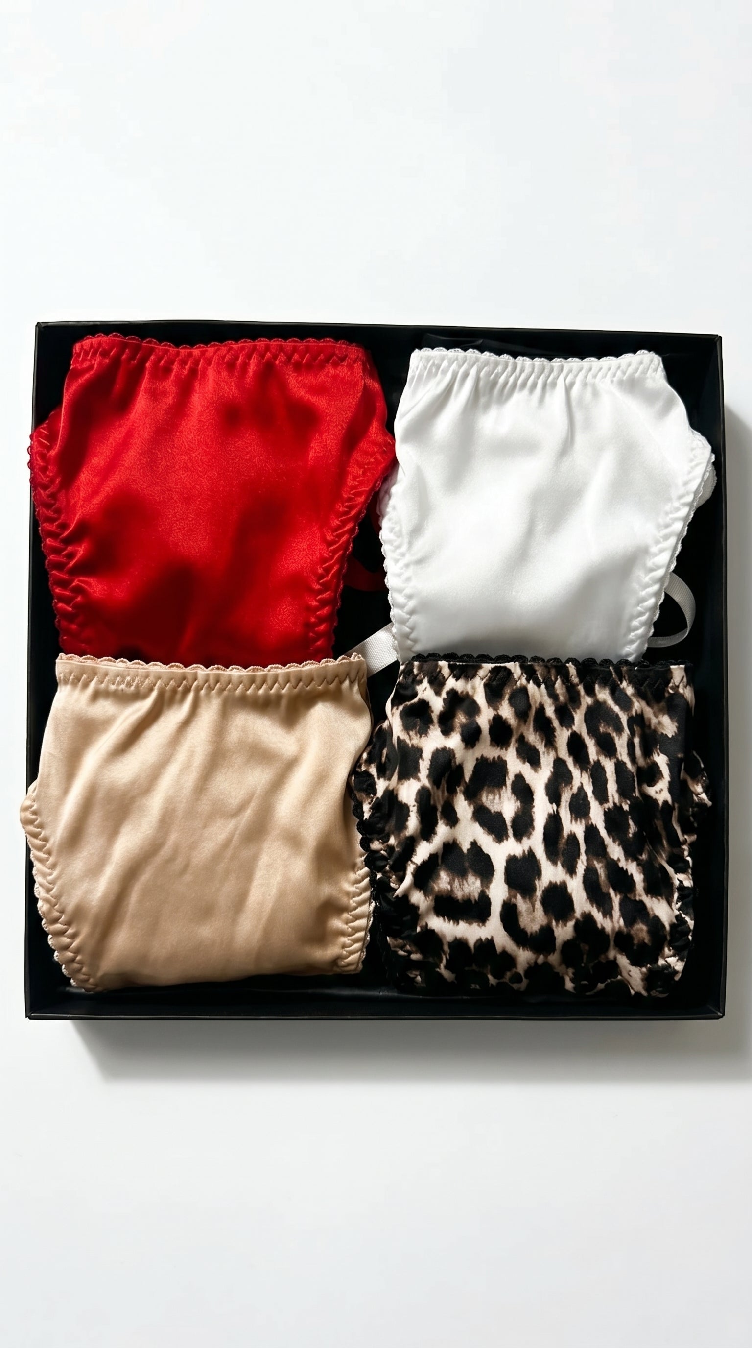 Artisanal multicolor Silk Box set featuring four handcrafted panties in red, white, beige, and leopard print.